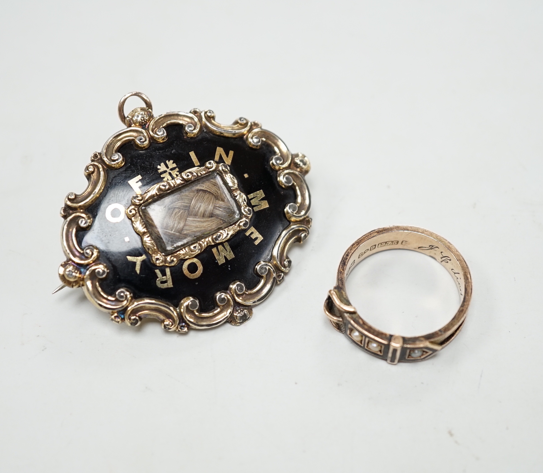 A Victorian 9ct gold, black enamel, plaited hair and seed pearl set mourning buckle ring, size P and a similar yellow metal brooch